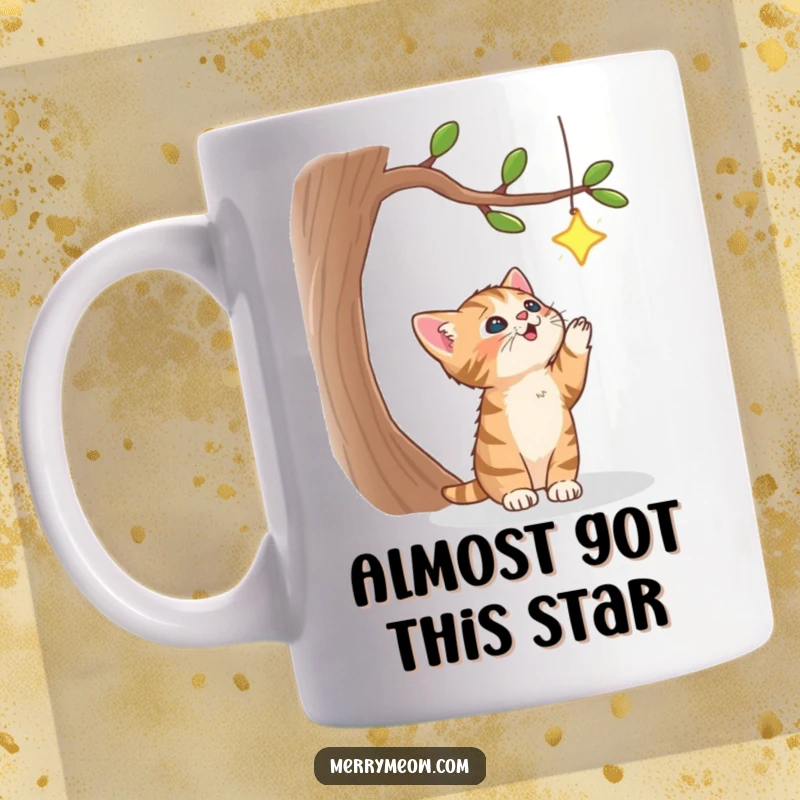 Funny mug featuring a determined tabby kitten leaping to catch a sparkling star dangling from a whimsical tree, embodying playful aspiration.