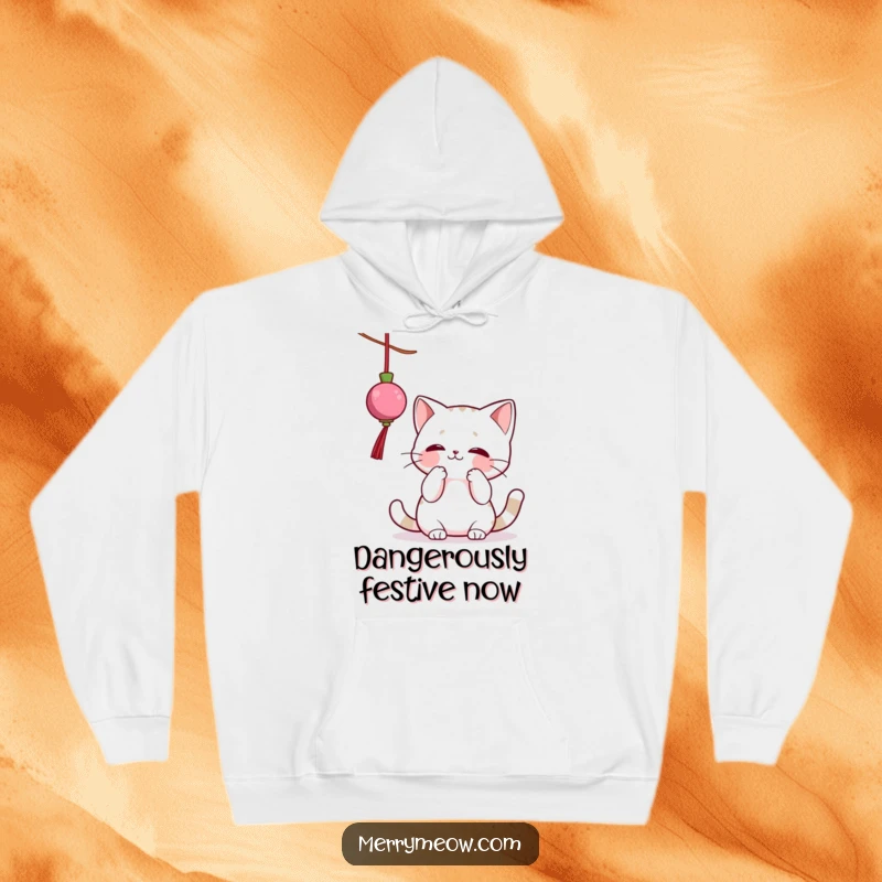 Funny hoodie depicting a fluffy cat character joyfully batting at a dangling Christmas ornament, perfect for cozy, humorous holiday wear.