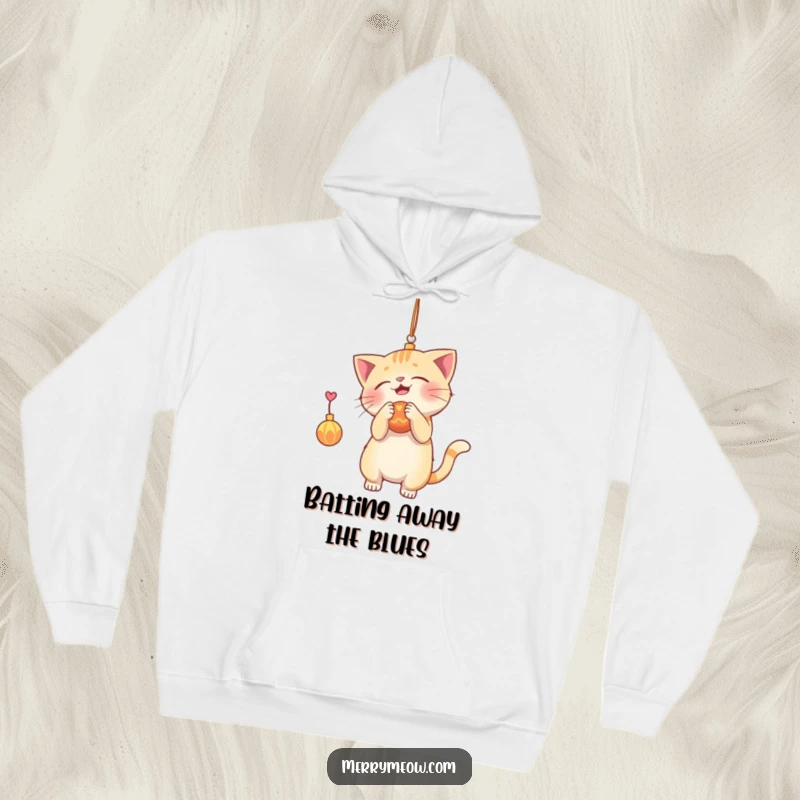 Funny hoodie print of a playful cat batting at a shiny Christmas ornament, offering cozy warmth and holiday cheer.