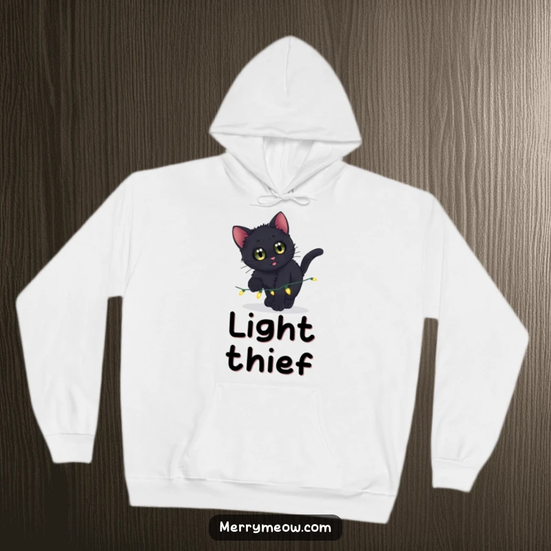 Funny hoodie showing a curious black kitten pouncing on sparkling Christmas lights, offering warmth and humor.