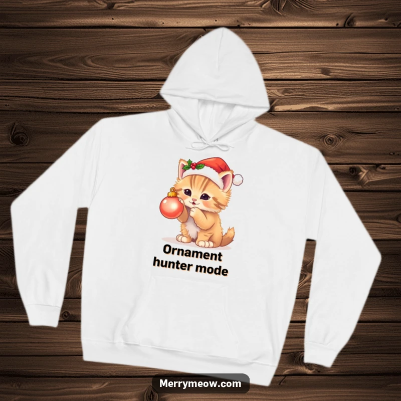 Funny hoodie showcasing a fluffy kitten in a Santa hat batting at a twinkling ornament, embodying adorable Christmas chaos.