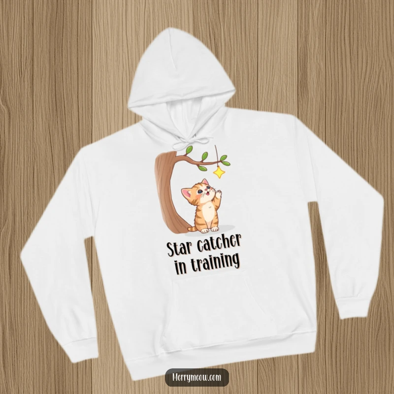 Funny hoodie depicting a fluffy tabby kitten mid-leap, eyes fixed on a bright star in a celestial tree, radiating warmth and ambition.