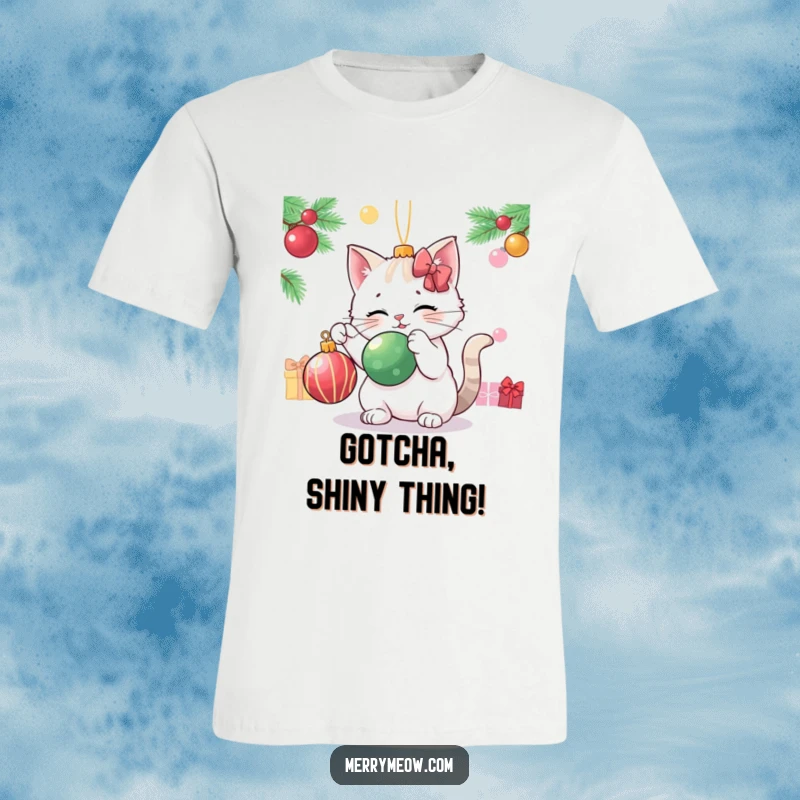 Funny cat playfully swatting at a dangling Christmas ornament, printed on a festive t-shirt.
