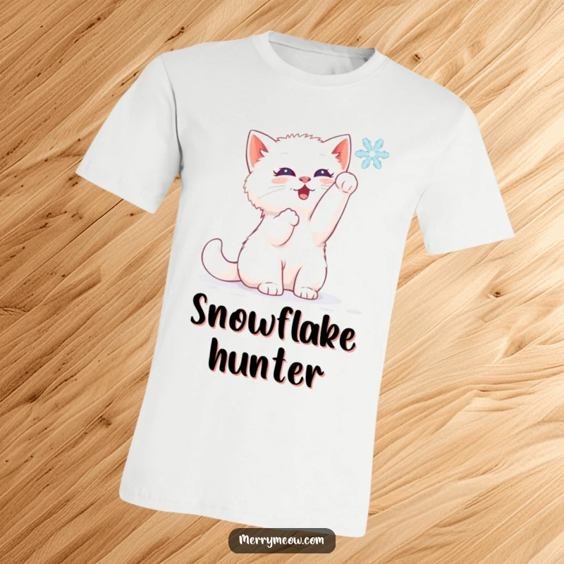 Funny t-shirt showing a happy white kitten playfully batting at a delicate snowflake falling from the sky.