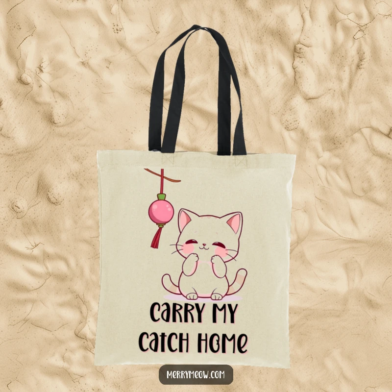 Funny tote bag featuring a lively cat character playfully swatting at a dangling Christmas ornament, ideal for stylish, humorous carrying.